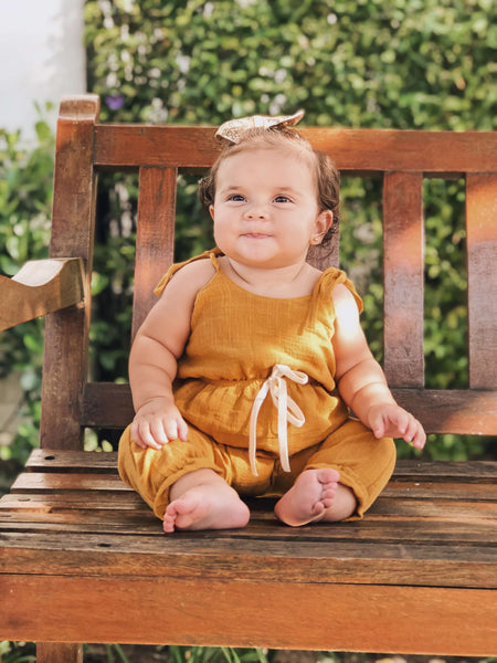 Menina com Macacão Saruel Trend Mostarda Este macacão Saruel para meninas é feito em um tecido de algodão muito leve e macio, na cor mostarda. Jardineiras online para infantil e bebes